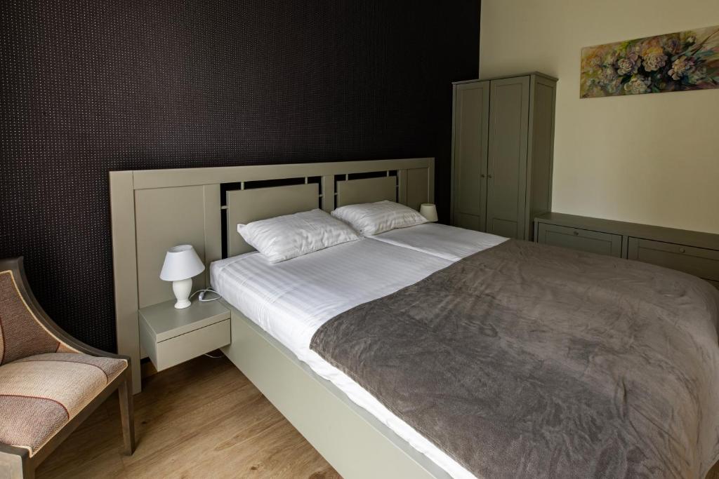 a bedroom with a large bed and a chair at Apartments of Vilhelm in Rīga