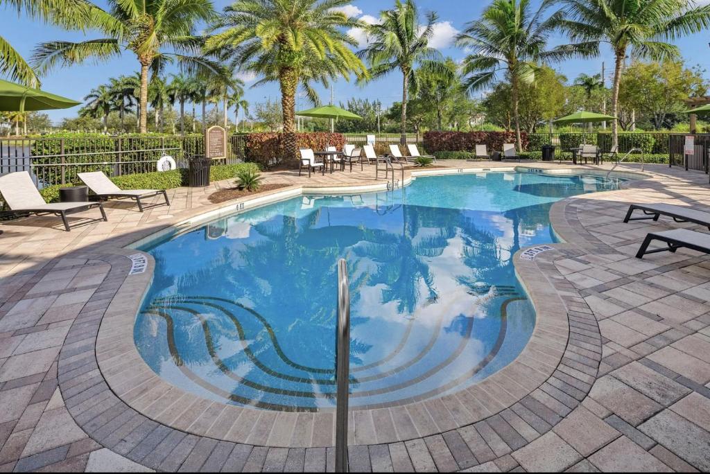 a swimming pool with chairs and palm trees at Miramar Apartments by Landing in Miramar