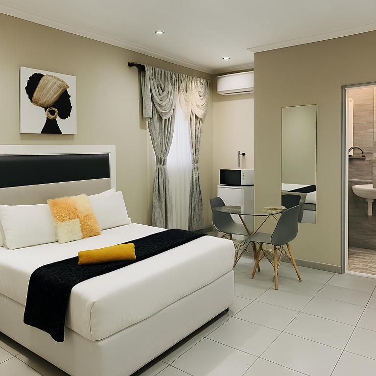 a bedroom with a white bed and a desk at U And I GuestHouse in Empangeni