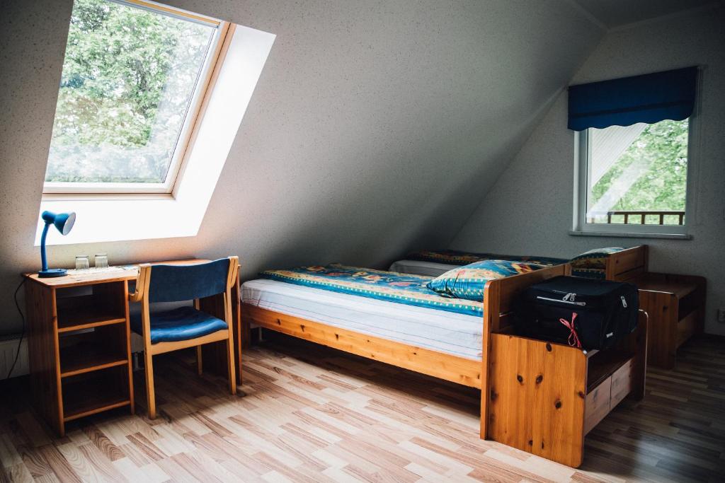 Jõesuu玫瑰河别墅酒店的一间卧室，配有一张床、一张书桌和一扇窗户