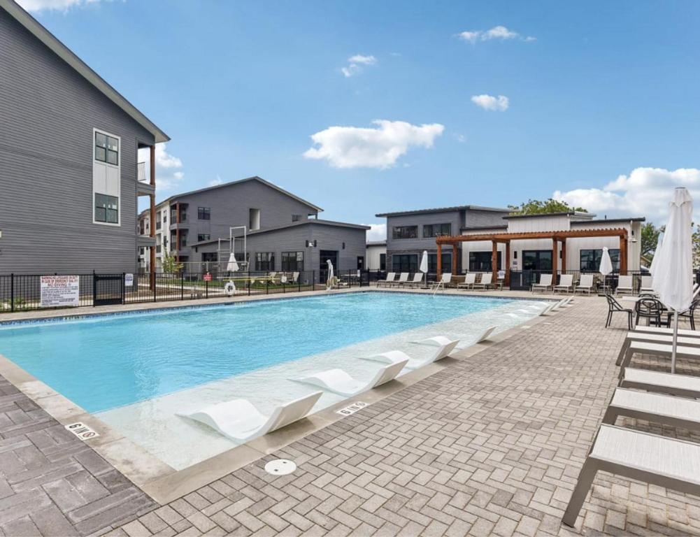 een zwembad met ligstoelen en een gebouw bij Landing Apartments - Seguin in Seguin