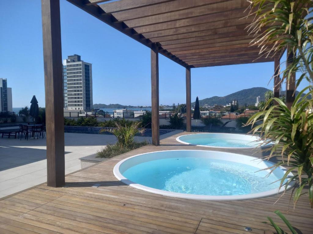 a hot tub on a deck with a pergola at Horizonte Infinito - Skyline Comfort Club - Penha in Penha