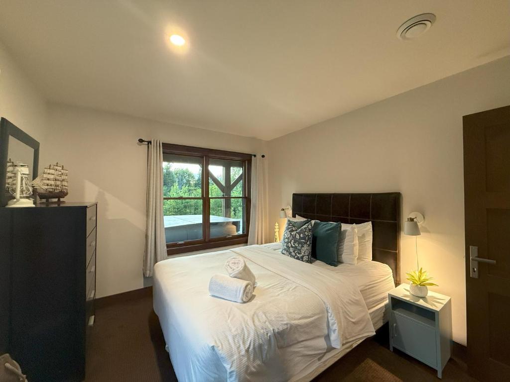 ラック・シュペリュールにあるChalet Inukshuk Luxury Log Cabin with Spa Lake View and Club Access near Mont Tremblantの窓のある大きな白いベッドのある寝室
