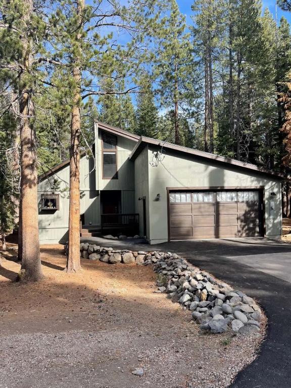 a white house with a garage and a tree at Glacier Forest Getaway HOA Access in Truckee