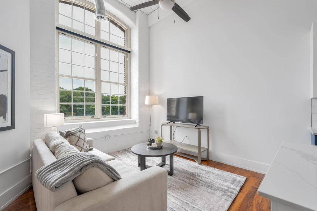 ein weißes Wohnzimmer mit einer Couch und einem Tisch in der Unterkunft Landing Apartments - Greenville in Greenville