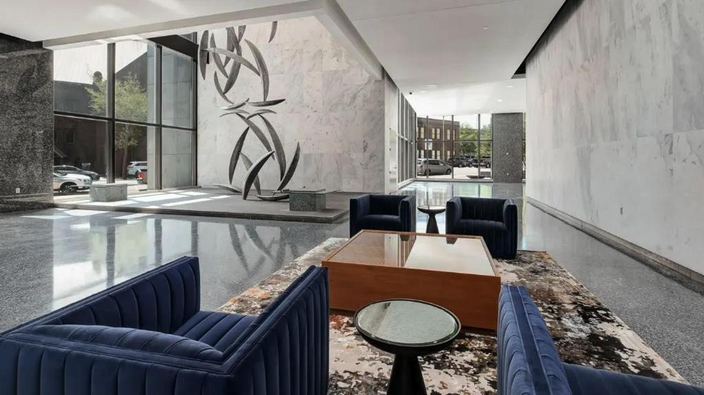 Una sala de estar con dos sillas azules y una mesa. en Downtown Birmingham Apartments by Landing, en Birmingham