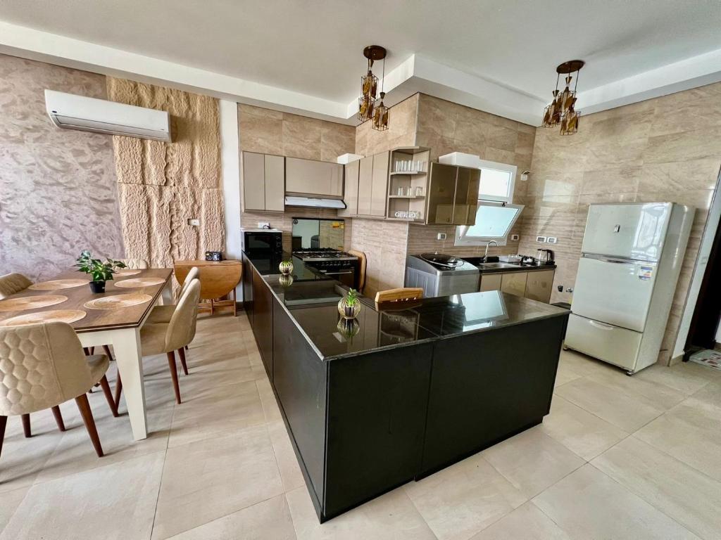 エル・アラメインにあるModern Furnished Apartment Mazarine North Coastのキッチン(黒いカウンタートップ、テーブル付)