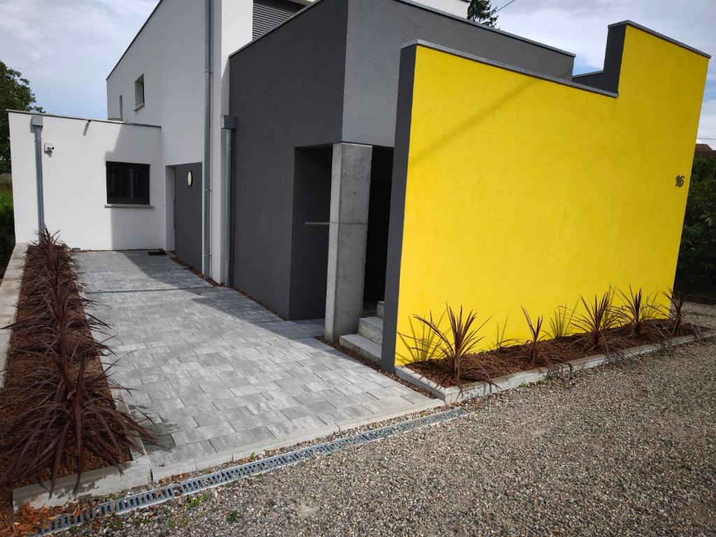 un mur jaune à côté d'un bâtiment blanc dans l'établissement Près colmar 6, à Wolfgantzen