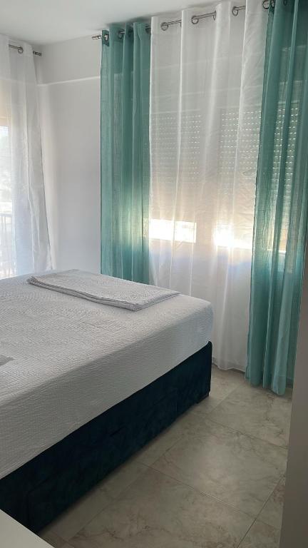 a bedroom with a bed with white curtains and a window at MBv Budva in Budva
