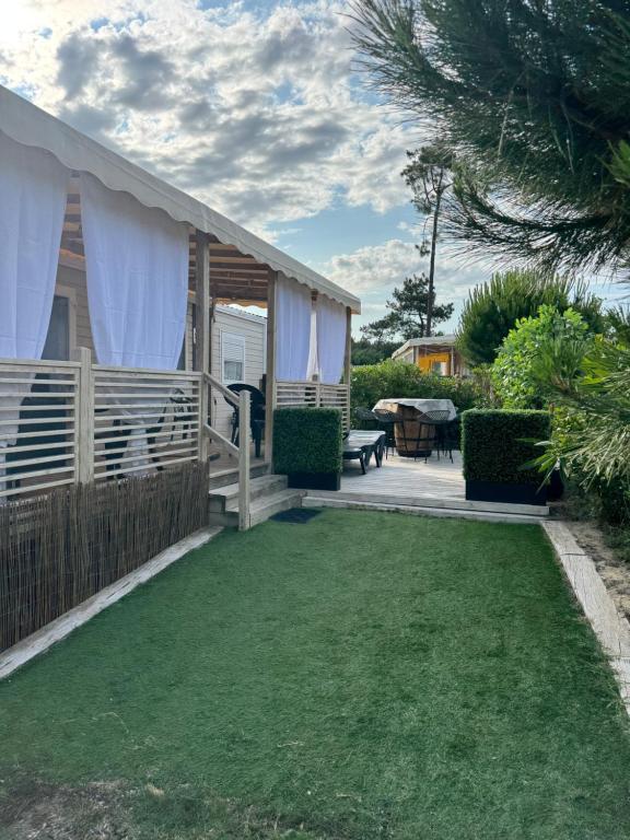 a house with a patio and a yard with grass at Mobil home Cap ferret les viviers siblu in Lège-Cap-Ferret