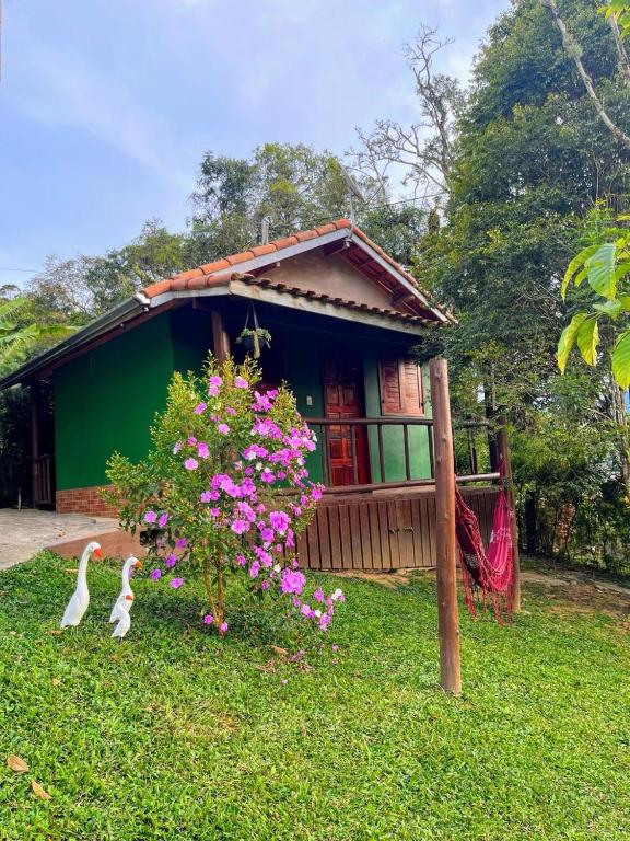 a house with two swans in front of it at Chalé da Flor in Visconde De Maua