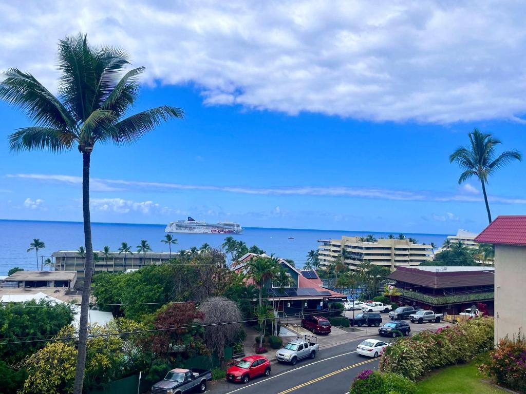 a view of a city with a palm tree and the ocean at Kona Mansions - Ocean Views & Amenities in Kailua-Kona