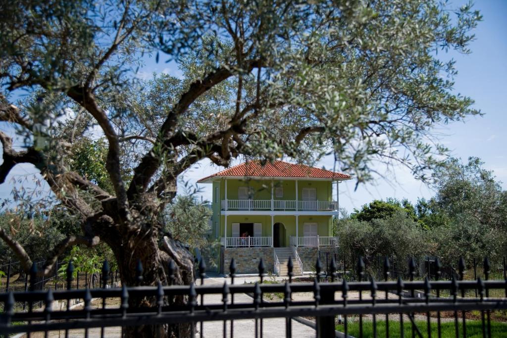 una casa gialla con un albero di fronte di Olivegrove House a Vourvourou