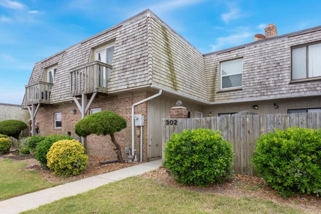 a house with a wooden fence and bushes at SC302 - Kitty Hawk Flyer in Kitty Hawk