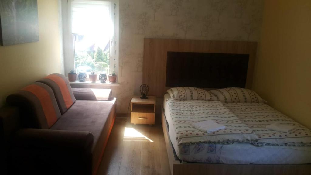 een slaapkamer met een bed, een bank en een raam bij Stacja Roman in Karpacz