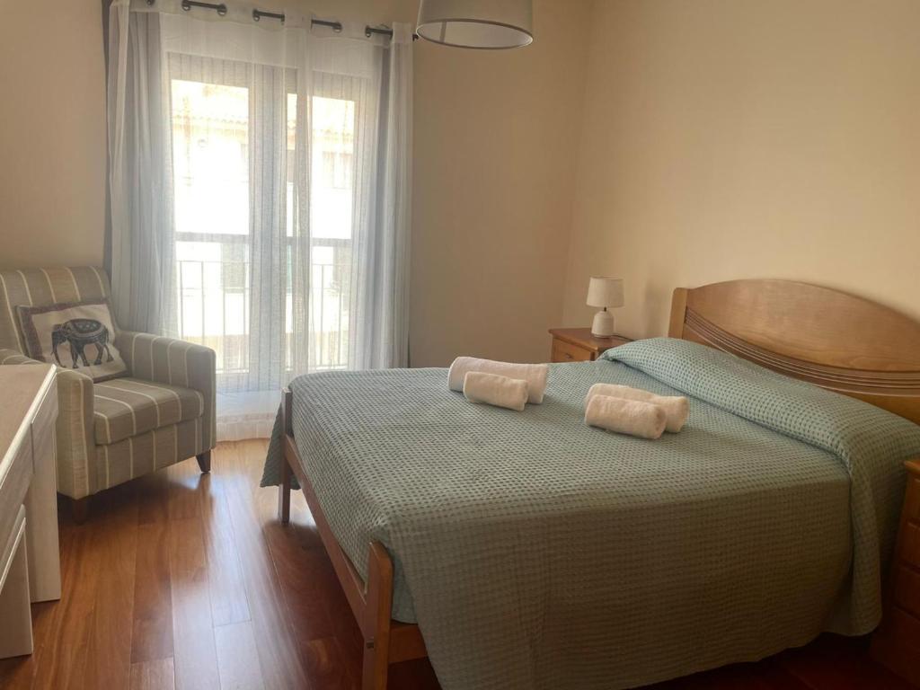 a bedroom with two beds and a chair and a window at Paraíso Altântico in Machico
