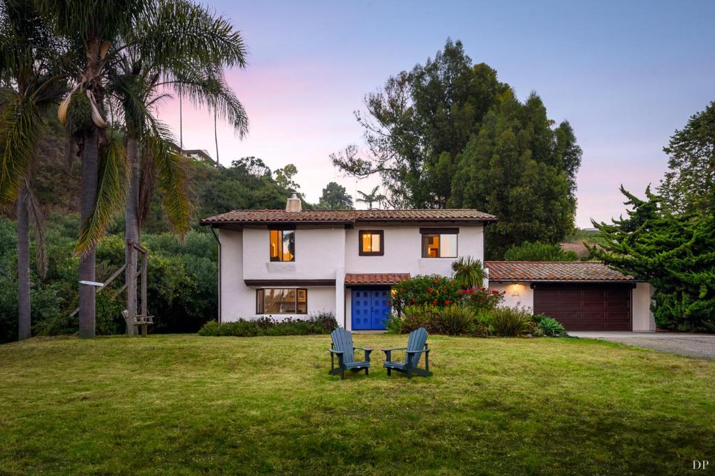 a house with two chairs in front of a yard at Sea Change by Paradise Retreats in Santa Barbara