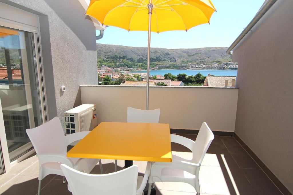 een gele tafel en stoelen met een parasol op een balkon bij Apartment Villa Franci in Pag