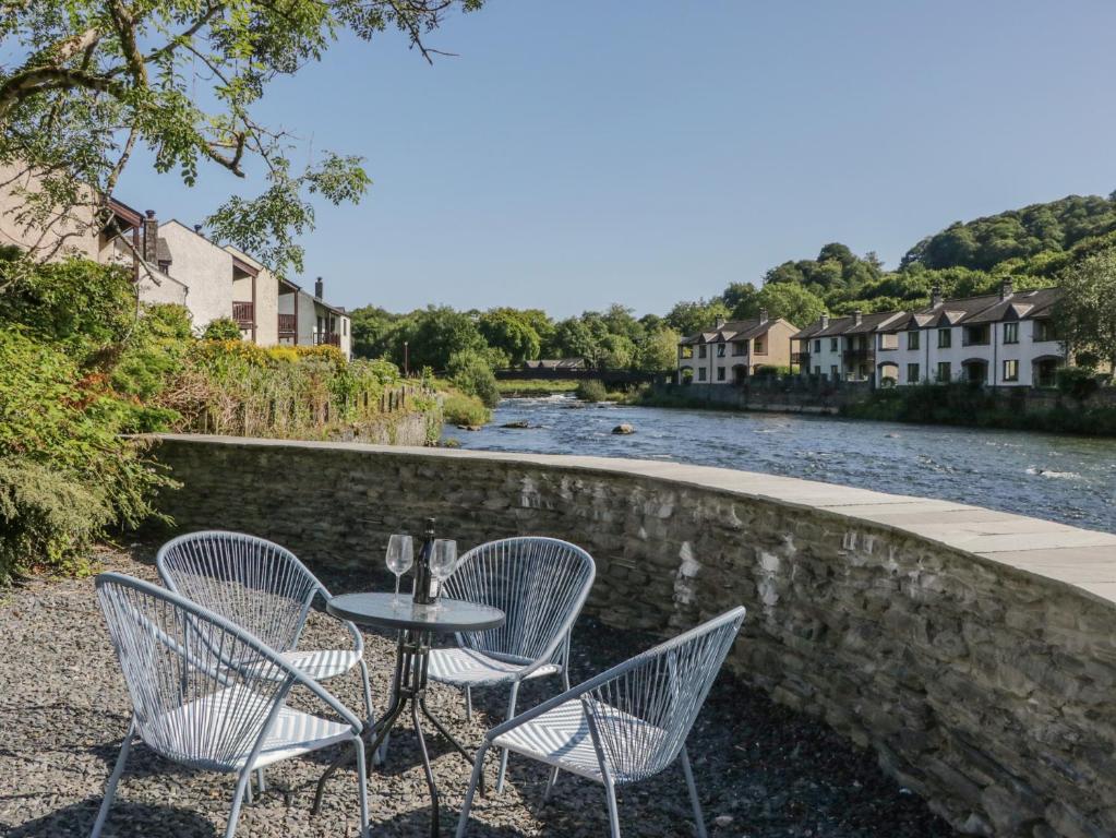 une table et des chaises assises à côté d'une rivière dans l'établissement Old Post Office Cottage, à Ulverston