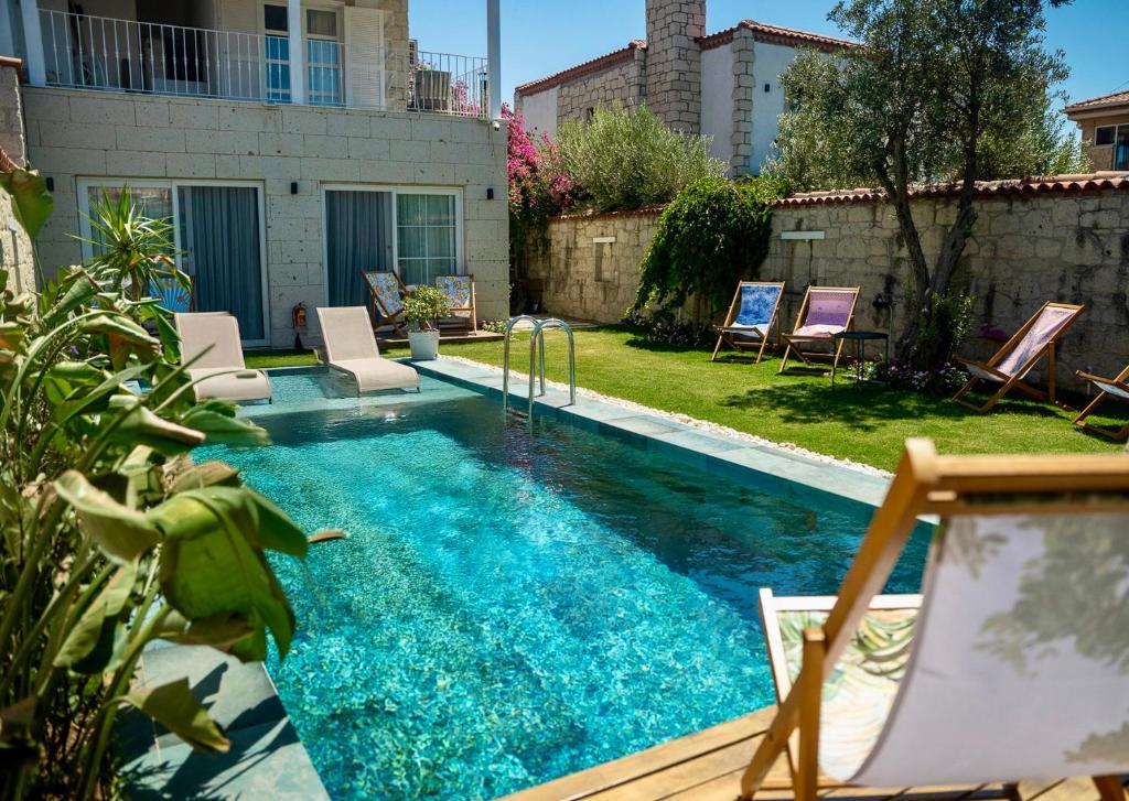 ein Pool in einem Garten mit Stühlen um ihn herum in der Unterkunft Noesta Alaçatı in Alacati