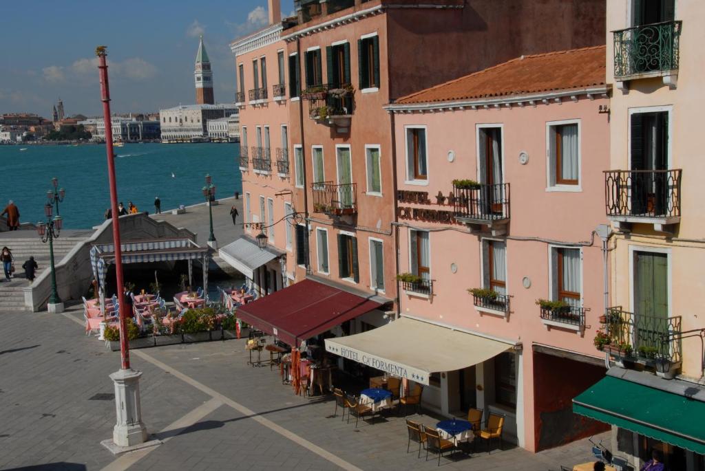 a group of buildings with tables and chairs near the water at Hotel Ca' Formenta in Venice