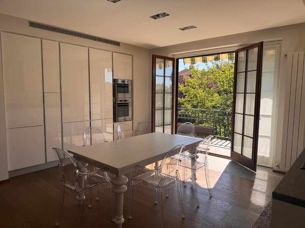 a dining room with a table and chairs and a balcony at Ampio Appartamento con vista lago, sauna e camino Golf club Margara in Fubine