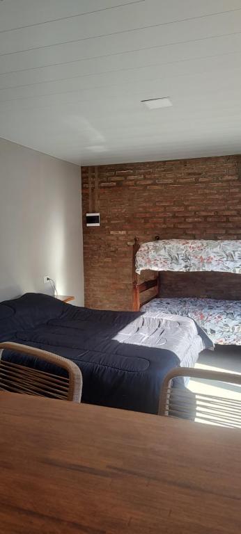 a bedroom with two beds and a brick wall at OMA Departamentos por día -2 in Utracán