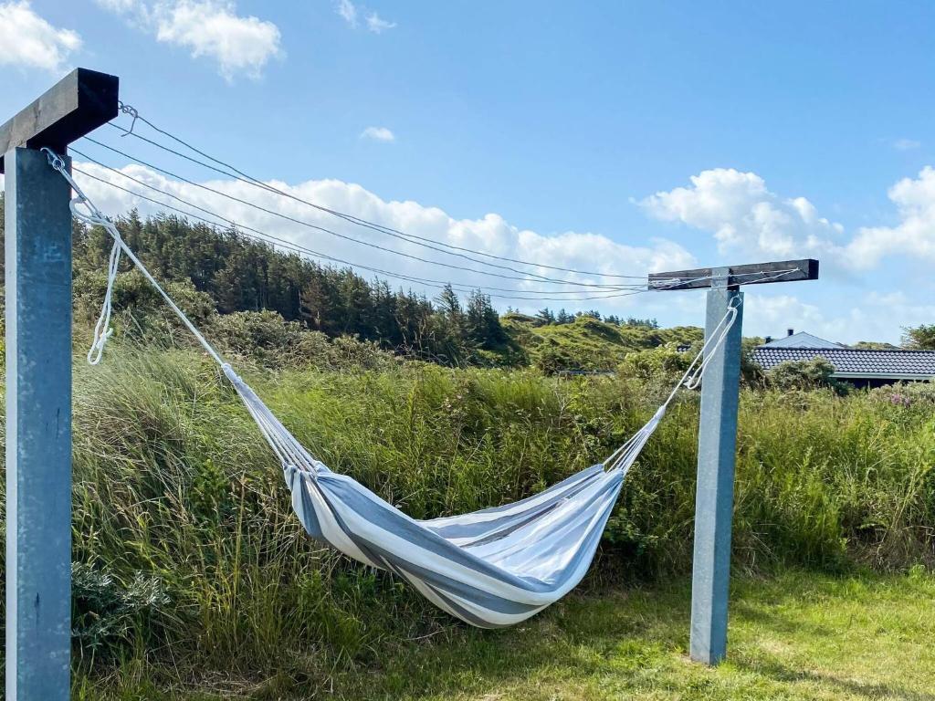 a hammock tied to a pole in a field at Cozy Coastal Retreat - By Traum Ferienwohnungen in Hjørring
