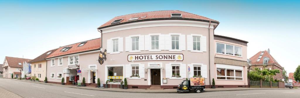 un bâtiment rose au coin d'une rue dans l'établissement Hotel Sonne, à Stupferich