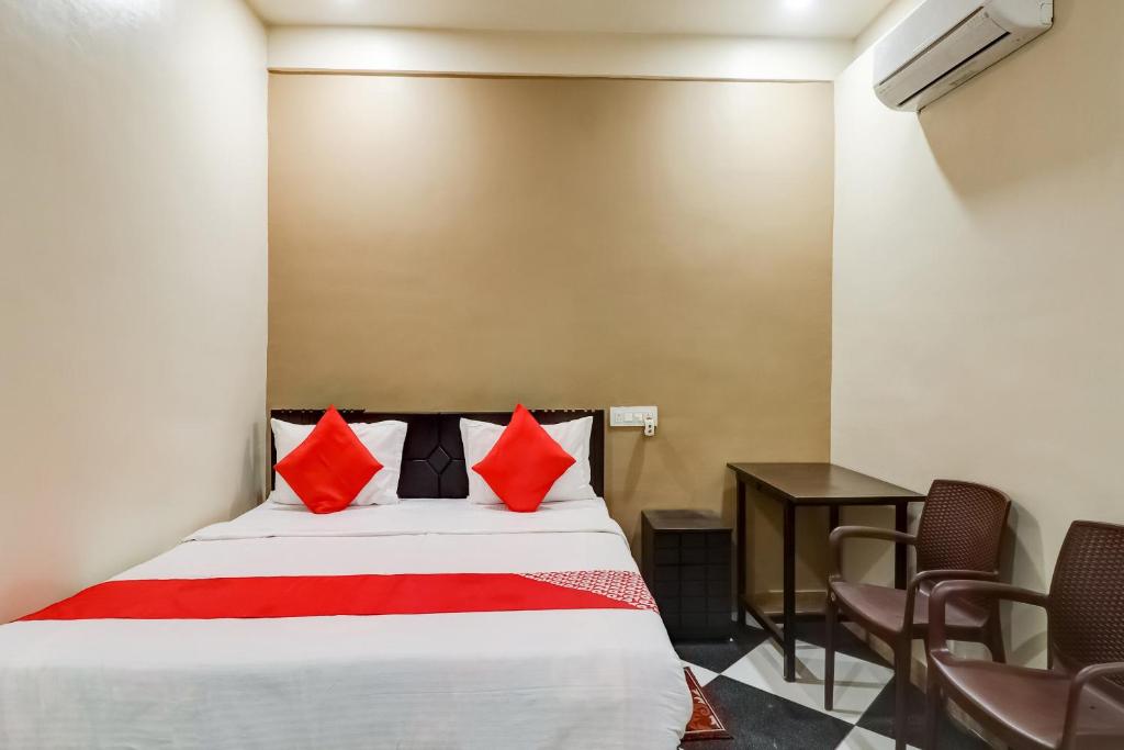 a bedroom with a bed with red pillows and a table at Hotel O Mini Punjab Hills in Jamshedpur