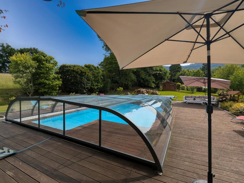 ein Regenschirm auf einem Deck neben einem Pool in der Unterkunft Chambre familiale avec piscine et SPA à Anould - FR-1-589-708 in Anould