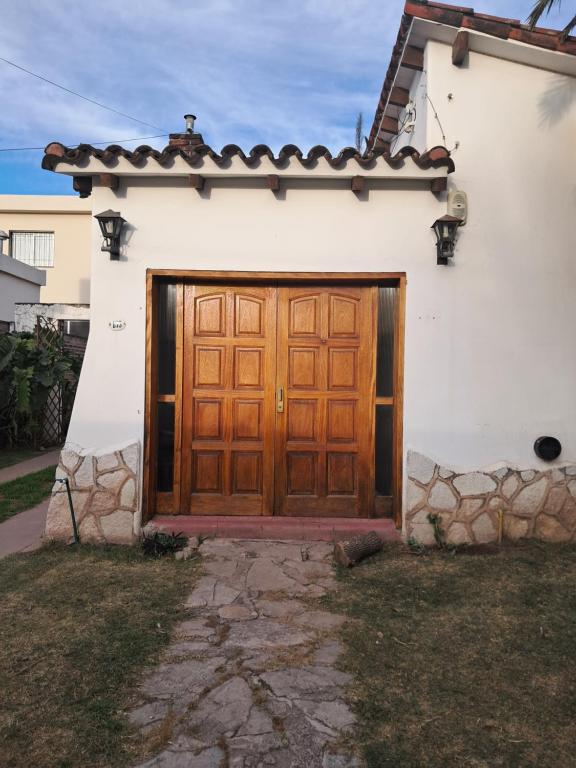 ein weißes Haus mit einer hölzernen Garagentür in der Unterkunft La Casa de María Helenra in Alta Gracia