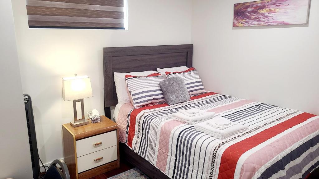 una camera da letto con un letto e un comodino con una lampada di Two luxury bedrooms in the basement a Winnipeg