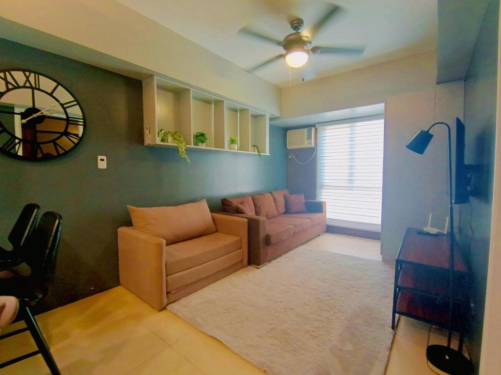 a living room with a couch and a clock on the wall at 1205T2 Avida Riala IT Park 1BR Unit 400Mbps Internet in Cebu City