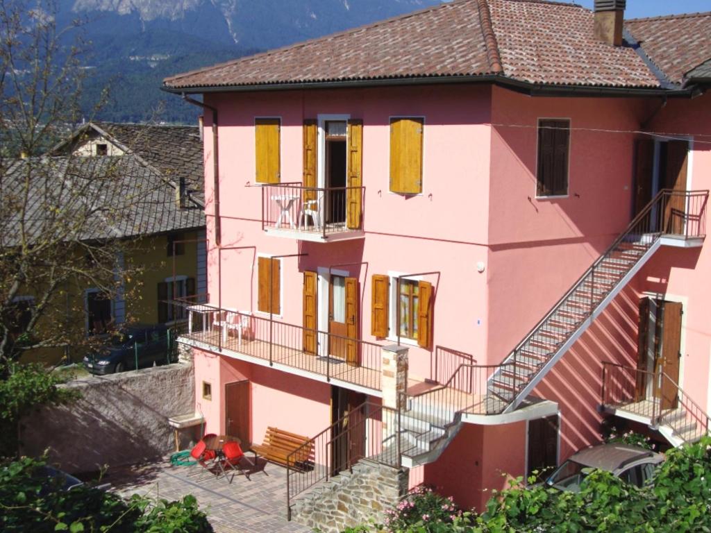 a pink house with yellow shutters and stairs at Appartamenti Nadalini in Levico Terme