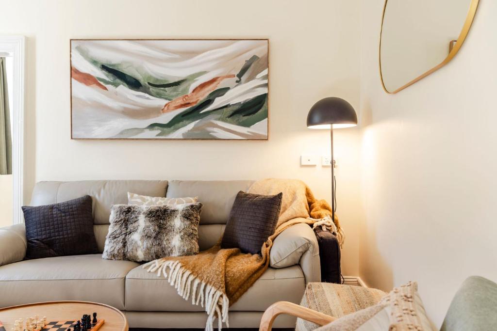 a living room with a couch and a painting on the wall at Rivulet Retreat - Cosy South Hobart Home & Parking in West Hobart