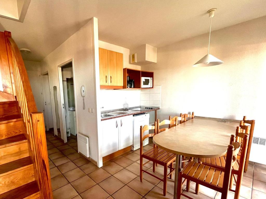 Una cocina y un comedor con mesa y sillas. en Appartement 6 pers avec vue Socoa et terrasse - FR-1-239-1142, en Ciboure