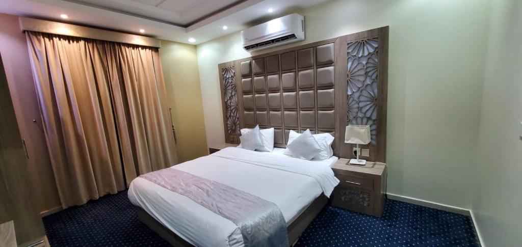 a hotel room with a bed and a television on the wall at شاليهات وشقق ليالي رهيف in Abha
