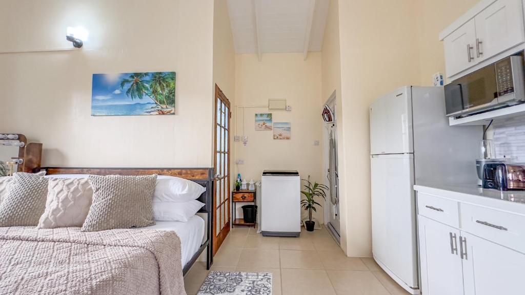 una cucina con frigorifero e un letto in una camera. di Country Rest - 8 min Drive from UVF Airport a Vieux Fort