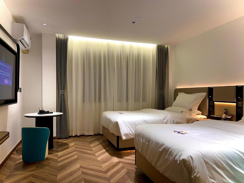 Una habitación de hotel con dos camas y un televisor de pantalla plana. en Haiman Hotel海曼酒店, en Bangkok