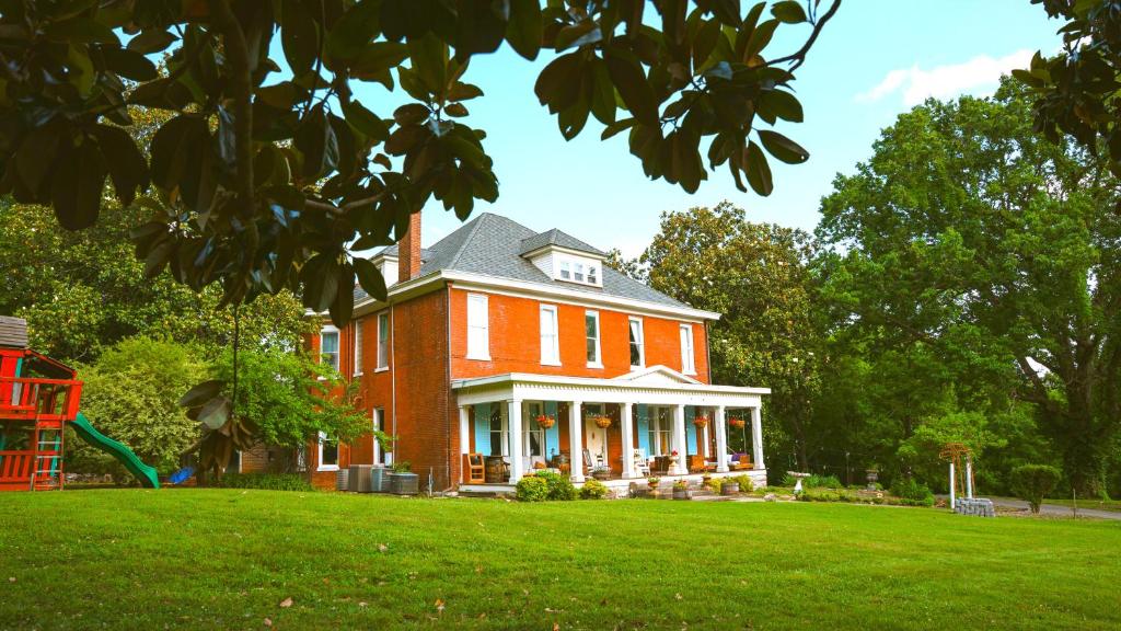 a large red brick house on a green lawn at The Magnolia Mansion 6 Minutes to Broadway on 4 Acres in Nashville