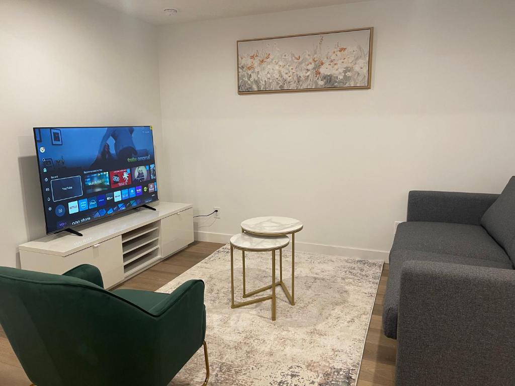 YYCにあるWestminister Manorのテレビ、ソファ、テーブルのあるリビングルーム