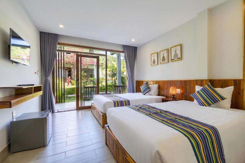 une chambre d'hôtel avec deux lits et un balcon dans l'établissement Suối Mây Garden Resort & spa, à Duong Dong