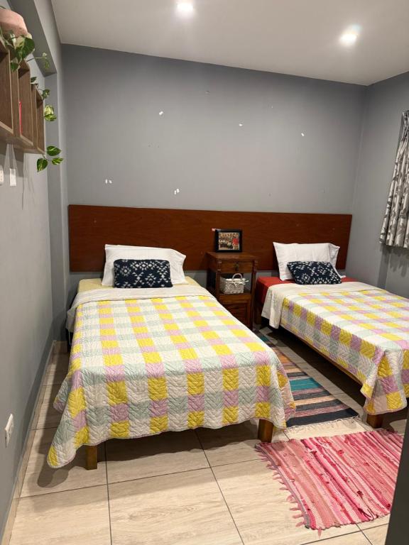 a bedroom with two beds and a rug at CasaHotel Chaclacayo in Chaclacayo