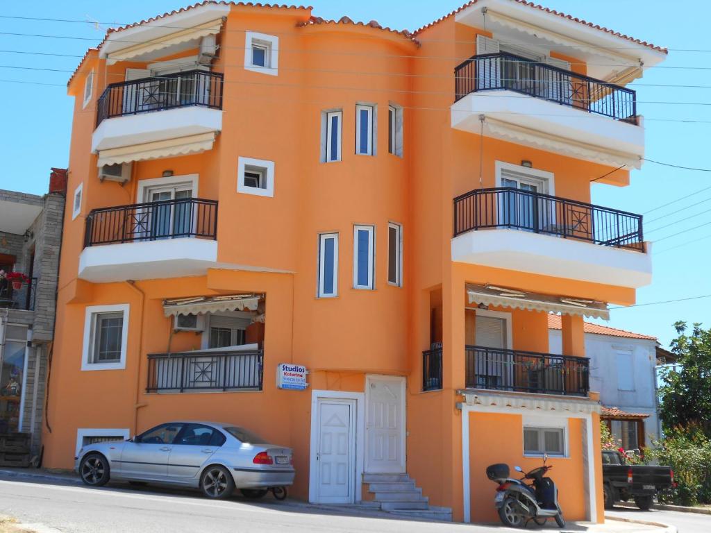 an orange building with a car parked in front of it at Katerina Studios in Limenaria