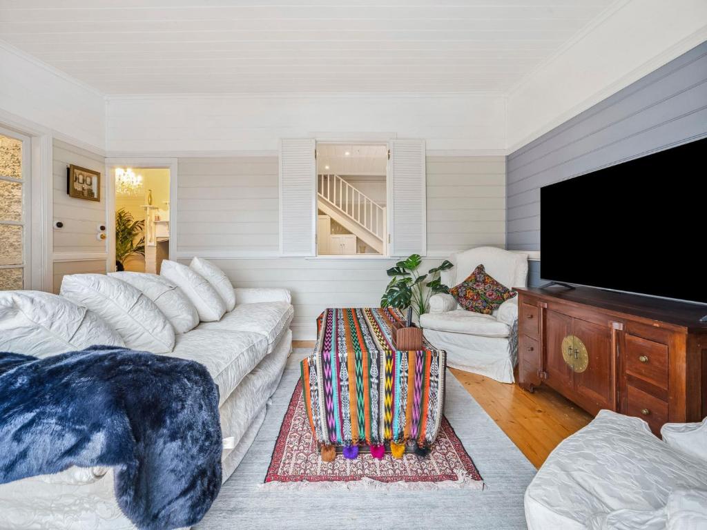 a living room with white furniture and a flat screen tv at Broughton Cottage in Katoomba