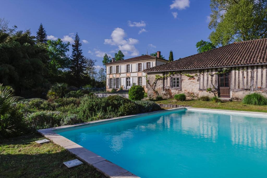 a swimming pool in front of a house at Domaine de la Grotte in Sore