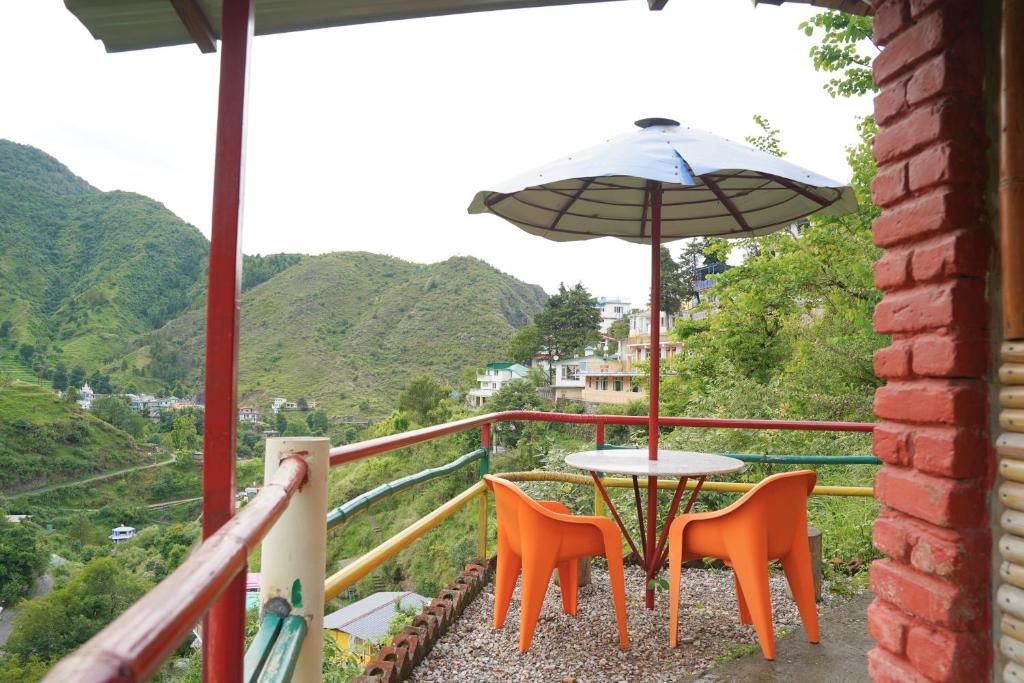 a table and chairs with an umbrella on a balcony at The Mud house, Mussoorie in Mussoorie
