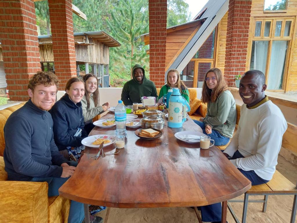 a group of people sitting around a wooden table at Chameleon Eco Farm Stay and Cultural Tours in Lushoto