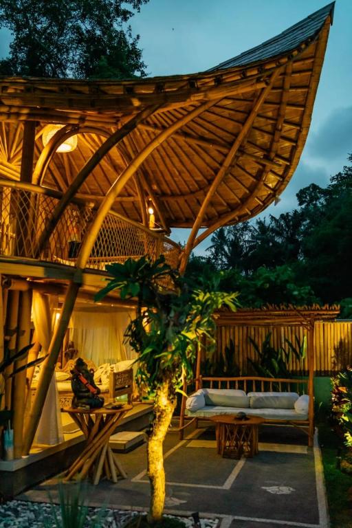 a wooden pavilion with a bench and a tree at Villa Rosebud in Sukawati
